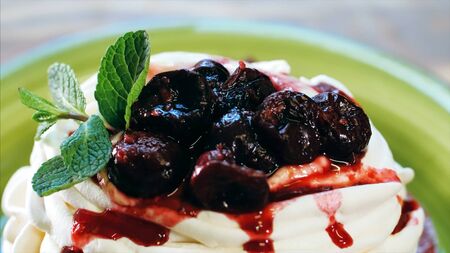 Appetizing meringue cake with cream and cherry jam on top, close-up.の写真素材