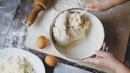 Close-up hands of senior female is kneading a dough at home kitchen, above viewの写真素材