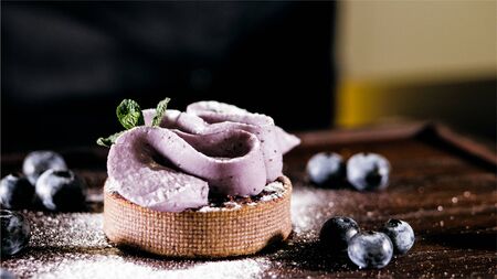 Cake with purple cream on the table near the blueberries, close-up.