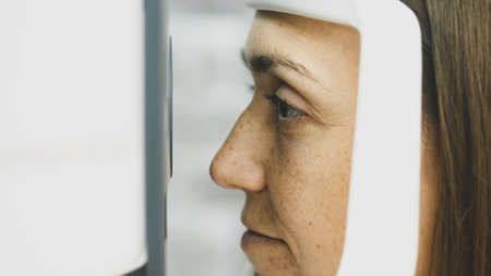 Close-up portrait of woman during test of refractometer machine.の写真素材