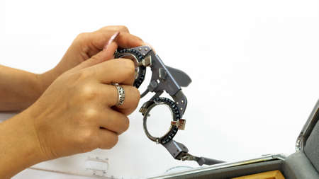 Female hand picking a lens to perform an eye exam.