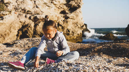 Happy little girl enjoying summer vacation and playing seashells on the beach.の写真素材