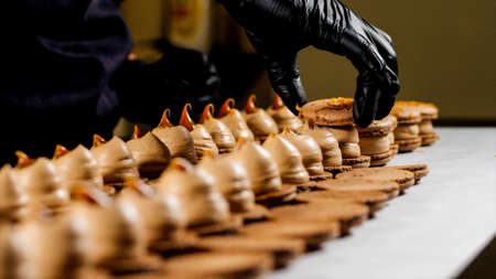 Chef is assembling caramel macarons, close-up.の写真素材