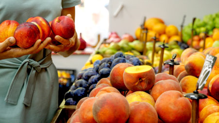 Young caucasian woman is choosing a nectarines at supermarketの写真素材