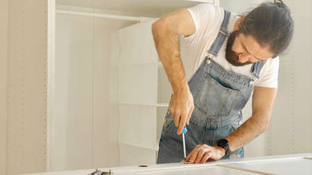 A man is installing the hinges on the doors of the closetの写真素材