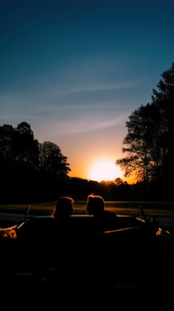 Silhouette of a couple on a convertible car at sunset.の写真素材