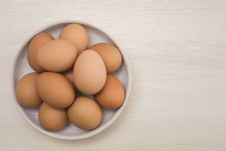 Fresh eggs on a bowl rustic background, wood spoon, weighing apparatus.The top view. View from...