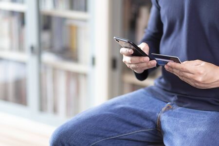 Man wear blue T-shirt Hands using smartphone and credit card.