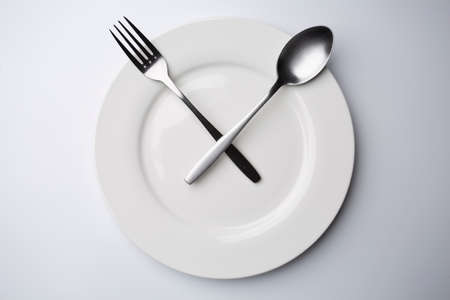 clock white plate with stainless spoon and fork eating time meal conceptの写真素材
