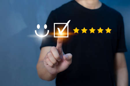 Satisfaction and customer service survey concept, business people using virtual screen. to answer the question And the satisfaction rating, the satisfaction rating with the smiley face icon 5 stars.の写真素材