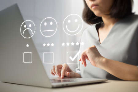 Satisfaction and customer service survey concept, business people using  laptop. to answer the questionnaire And the satisfaction rating, the satisfaction rating with the smiley face icon 5 stars.の写真素材