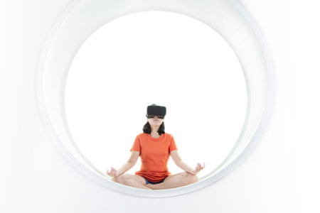 Women wearing virtual reality goggle glasses online metaverse technology. Relax with yoga traning at home modern interior.の写真素材
