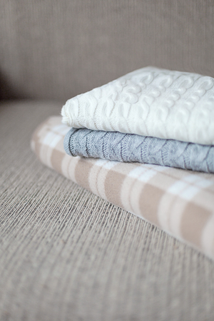 Woolen plaids or sweaters on a grey sofa, winter or autumn season.の写真素材