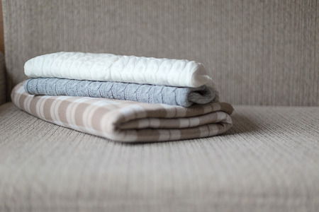 Woolen plaids or sweaters on a grey sofa, winter or autumn season.の写真素材