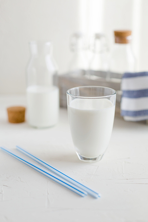 Cow or nut milk in a glass and bottles on white table in the kitchen.の写真素材