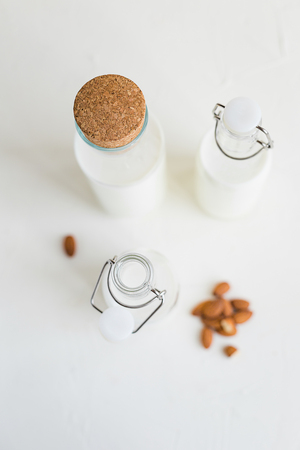 Cow or nut milk in a glass and bottles on white table in the kitchen.の写真素材