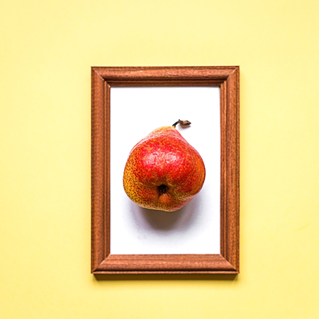 Red pear on yellow paper background,summer concept, wooden frameworkの写真素材
