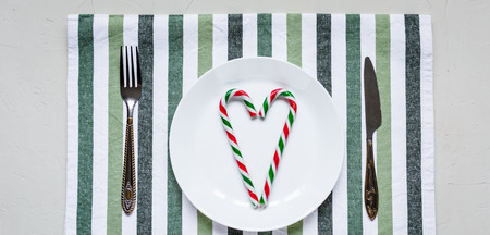 Table setting with stripped coton napkin, knife and fork.Decorated with green leafの写真素材