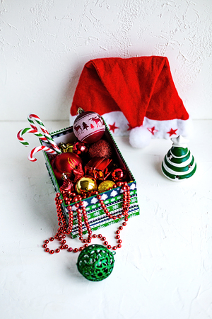 Some colorful Christmas toys ina box and around it on hite table. Holiday preparations.の写真素材