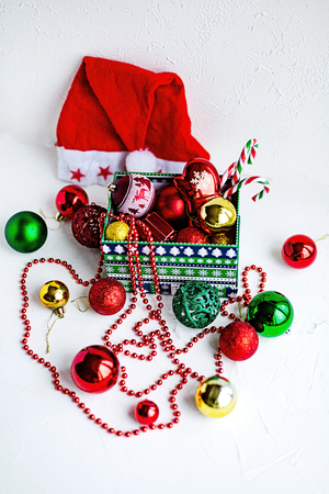 Some colorful Christmas toys ina box and around it on hite table. Holiday preparations.の写真素材