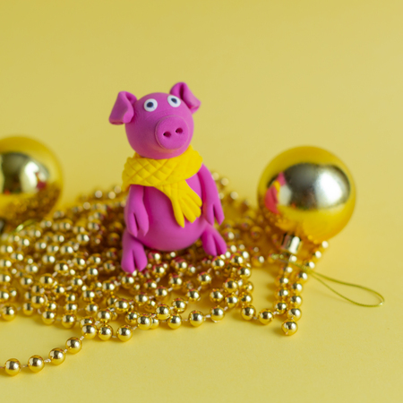 Hand made little plasticine pigs on colorful paper background. Symbol of a chinese new year and chinese holiday concept. Square image.の写真素材