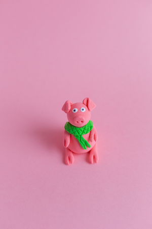 Hand made little plasticine pig on pink paper background. Symbol of a chinese new year and chinese holiday concept.の写真素材
