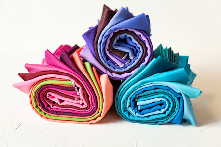 Colorful fabric rolled up on white background.