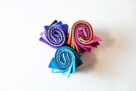 Colorful fabric rolled up on white background.