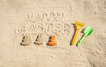 Text Happy Easter and several Easter bunnieas are on the sand.の写真素材