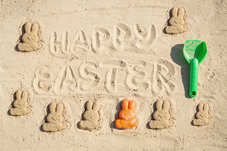 Text Happy Easter and several Easter bunnieas are on the sand.の写真素材