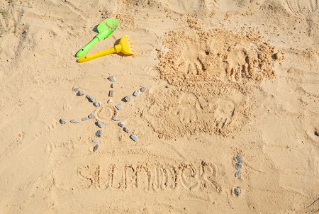 Top view of summer sand drawing . The sun and text Summer and two child handprint are on the sand.の写真素材