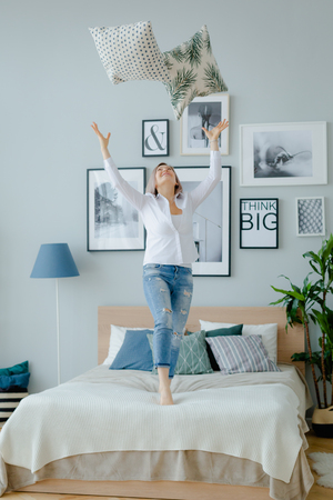 A blonde woman is jumping on the bedの写真素材