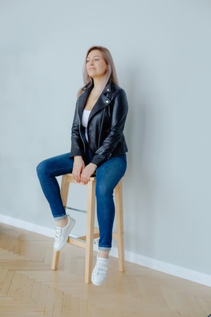 A blonde woman in a black leather jacket is sittingの写真素材