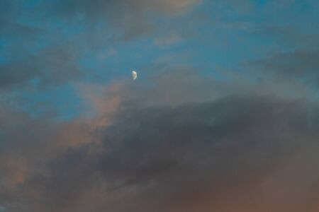 Evening colorful cloudy sky with the moon in the summer sunset.