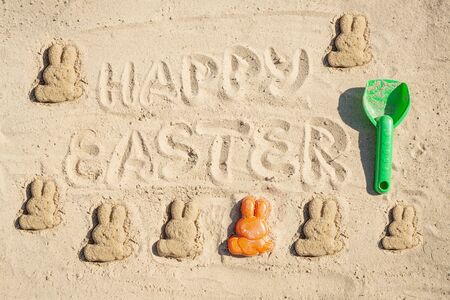 Text Happy Easter and several Easter bunnieas are on the sand.の写真素材