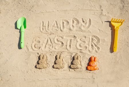 Text Happy Easter and several Easter bunnieas are on the sand.の写真素材