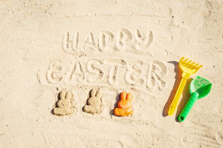 Text Happy Easter and several Easter bunnieas are on the sand.の写真素材