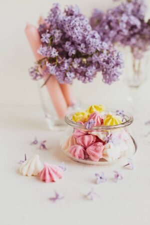 Purple spring lilac flowers still life  with candies on white background in the morning.の写真素材