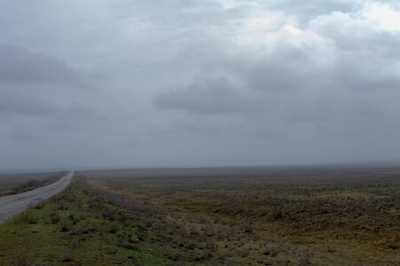Wide old road in the foggy steppe in spring early morning.の写真素材