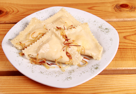 Cooked raviolli with mushrooms on a shiny white plateの写真素材
