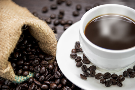 Coffee cup with  smoke and coffee beans in sack on wood table, Drinks and relax concept, for advertisingの写真素材