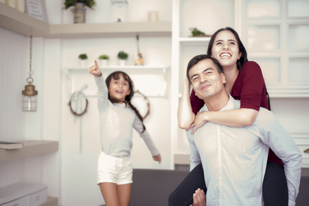 Happy family looking outside with happy moods, mom ride back on dad, girl pointing to the outside with happy face mood, Family and happiness concept  selective focusの写真素材