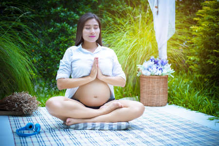 Pregnant woman doing yoga at the outdoor. Exercise and meditation conceptの写真素材