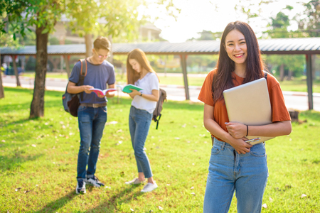 Three Asian young campus people tutoring and preparing for final examination in university. Education and learning concept. Friendship and Relation ship concept. College and Outdoors theme.の写真素材
