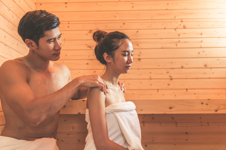 Young Asian couples or lovers have romantic relaxing in sauna room. Skin care heat treatment and body clean up and refreshing in spa with steam bath. Healthy and Honeymoon concept. Happiness togetherの写真素材