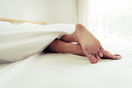 Barefoot of human on bed in morning. Single and Working people concept. Lazy day and Happiness home theme.の写真素材