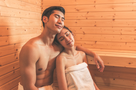 Young Asian couples or lovers have romantic relaxing in sauna room. Skin care heat treatment and body clean up and refreshing in spa with steam bath. Healthy and Honeymoon concept. Happiness togetherの写真素材