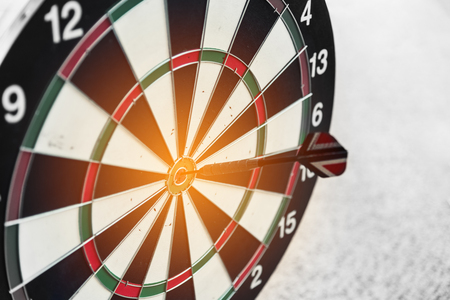 Dart board and arrow in middle. Business and success concept. Achievement and target theme. Orange sun light effect. High contrast toneの写真素材