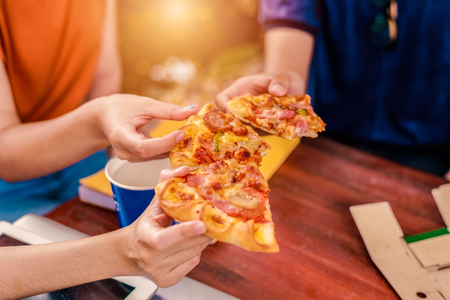 People celebrating with pizza in hand. Food and Friendship concept. Lifestyles themeの写真素材