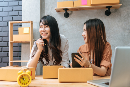 Two young Asian women startup small business entrepreneur SME distribution warehouse with parcel mail box. small  owner home office. Online marketing and product packaging and delivery serviceの写真素材